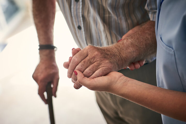 Female Nurse Supporting Senior Man To Walk